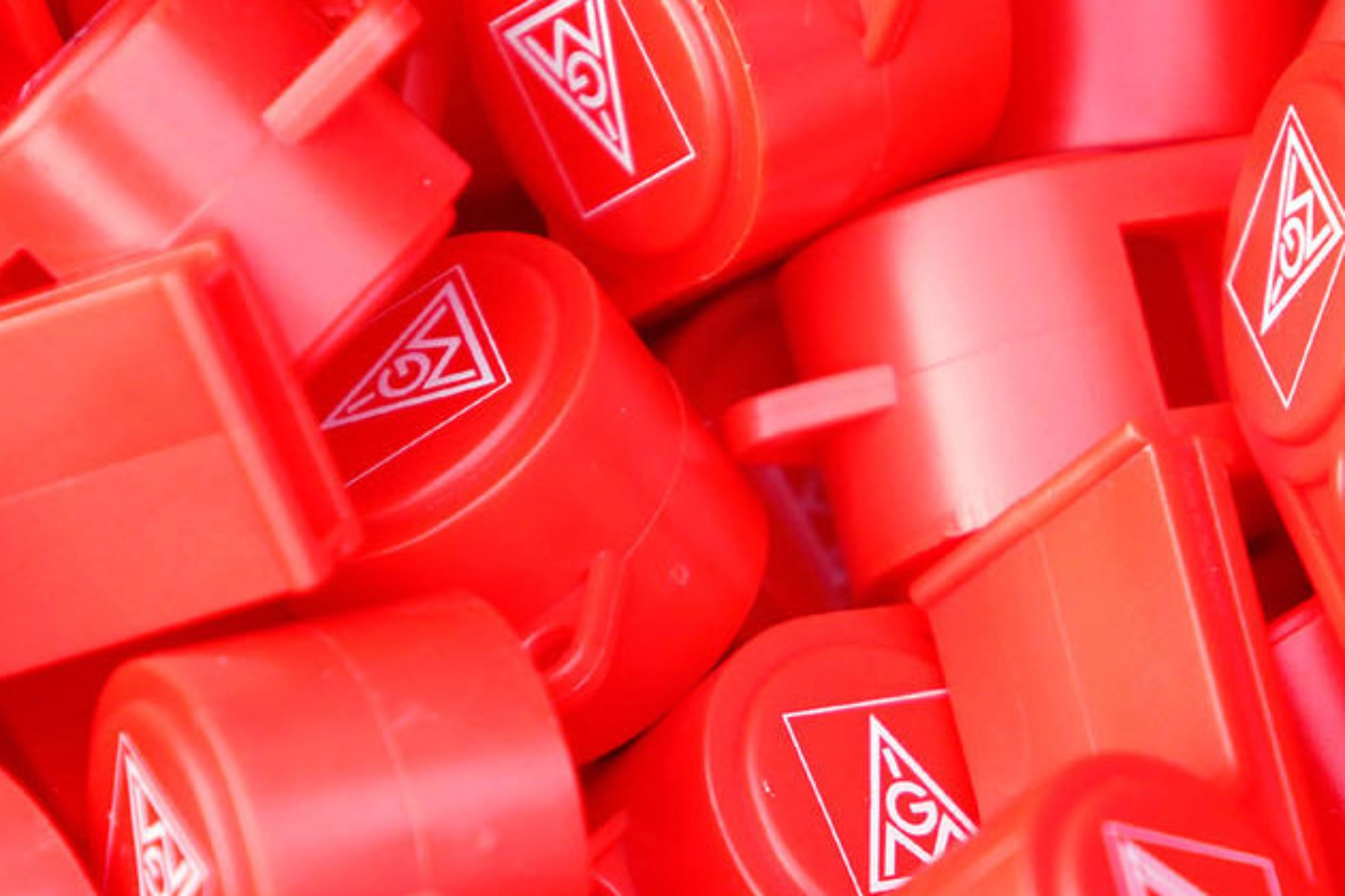 Viele rote Trillerpfeifen mit dem Logo der IG Metall. 